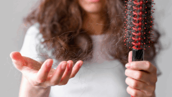 Mulher olhando para cabelos na escova capilar após quebra dos fios e queda