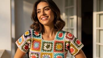 Mulher brasileira usando blusa de crochê colorida feita com squares, em ambiente iluminado por luz natural, representando moda artesanal moderna e criativa.