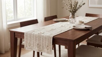 Caminho de mesa de crochê off-white sobre mesa de madeira nobre, sala elegante com cerâmica neutra e vaso com folhagem