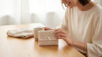 Mulher com carteira de crochê bege claro, ambiente editorial clean com joias minimalistas e madeira clara