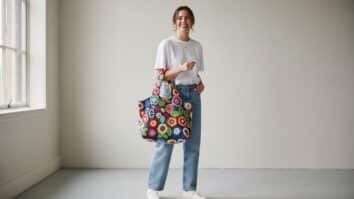 Mulher sorridente com bolsa jeans decorada com aplicações de crochê colorido em algodão, contraste urbano e criativo, luz natural e atmosfera contemporânea despojada.
