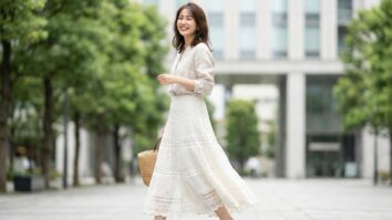 Mulher sorrindo usando saia de crochê branco em ambiente urbano de verão com luz natural