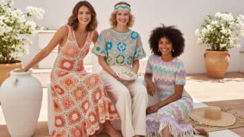 Mulheres sorrindo usando peças de crochê coloridas para o verão em ambiente iluminado com elementos decorativos sutis