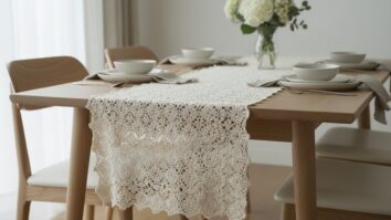 Sala de jantar acolhedora com caminho de mesa de crochê artesanal em algodão cru sobre mesa de madeira clara, louça neutra e vaso discreto