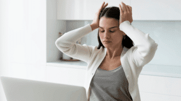 Mulher com as mãos na cabeça e semblante expressando tensão, simbolizando um momento de estresse