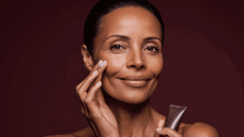 Mulher com pele madura e frasco de creme hidratante nas mãos