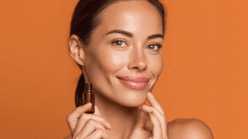 Mulher com frasco de sérum em uma das mãos, e exibindo uma pele bonita e viçosa