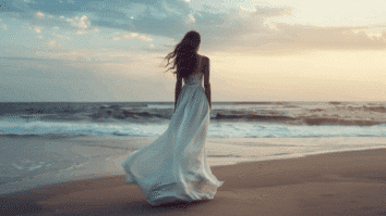 Uma mulher caminhando à beira-mar ao entardecer simboliza o ato de deixar o passado para trás e abrir espaço para um novo começo emocional