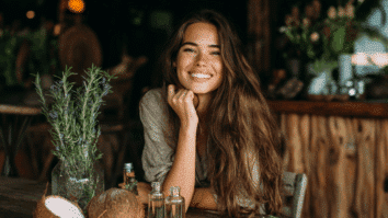 Mulher com cabelo comprido, óleos, coco e ervas em uma mesa