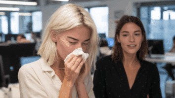 Mulher dizendo "Saúde" para uma colega que trabalho que espirrou