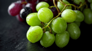 Uvas verdes e pretas fresquinhas e suculentas dispostas sobre uma mesa