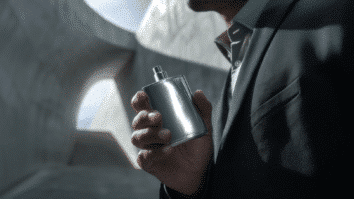 Homem com frasco de perfume de notas metálicas nas mãos