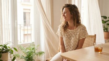 Mulher sorrindo usando blusinha de crochê clara em varanda iluminada com atmosfera de verão
