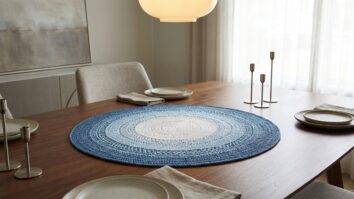Centro de mesa de crochê estilo mandala com degradê azul sobre mesa de madeira em sala de jantar elegante.