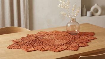 Centro de mesa de crochê laranja sobre mesa elegante com arranjo floral discreto