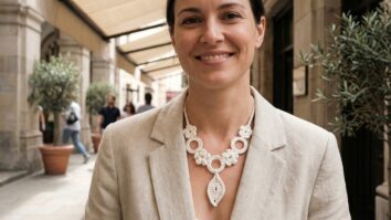 Mulher sorrindo usando colar de crochê branco com design moderno em ambiente urbano