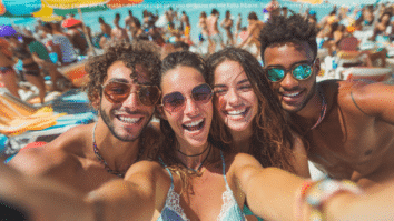 Um grupo de amigos sorrindo enquanto tiram uma selfie em uma praia em Ubatuba, com mar azul, guarda-sóis coloridos e clima vibrante de verão ao fundo