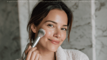 Mulher com pincel na mão aplicando base na pele para iniciar a maquiagem