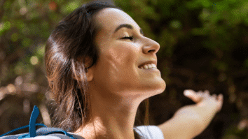 Mulher com semblante feliz em representação de uma mulher se sentindo bem consigo mesma e com sua a sua autoestima elevada