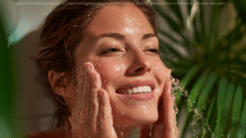Mulher sorrindo enquanto lava o rosto, transmitindo sensação de frescor e renovação