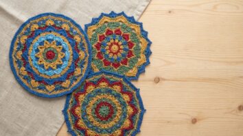 Vista superior de mesa com mandalas de crochê coloridas e simétricas dispostas harmonicamente.