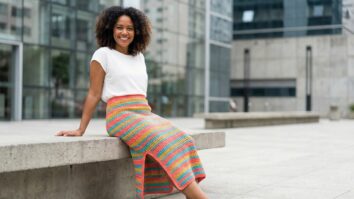 Modelo feminina sorrindo usando saia de crochê com fenda em ambiente urbano brasileiro