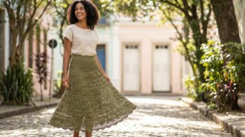 Modelo feminina sorrindo usando saia longa de crochê verde em ambiente urbano de verão
