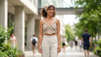 Mulher sorrindo com blusa e bandana de crochê colorida em ambiente urbano de verão
