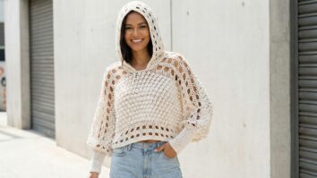 Mulher usando blusa cropped de crochê com capuz em tom off-white com texturas contrastantes