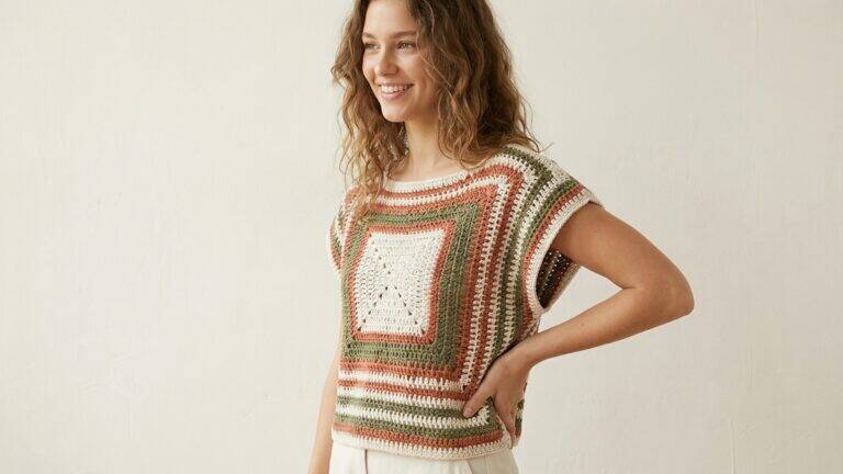 Mulher sorrindo usando blusinha de crochê com design geométrico em tons terracota e neutros modernos