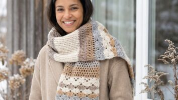 Mulher sorrindo usando cachecol de crochê em tons naturais em ambiente de inverno