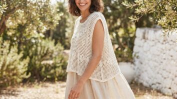 Mulher sorrindo usando colete de crochê off-white leve em ambiente de verão