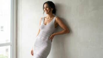 Mulher sorrindo usando vestido tubinho de crochê cinza claro elegante