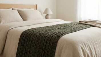 Quarto com peseira de crochê verde escuro em relevo sobre cama com roupa neutra