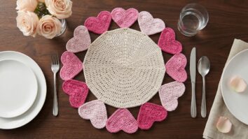 Mesa posta com sousplat de crochê com centro begeosta com sousplat de crochê com centro b e borda de corações em tons de rosa