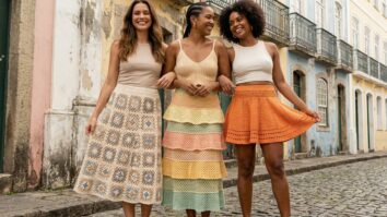 Três mulheres sorrindo usando saias de crochê em ambiente urbano de verão na Bahia