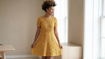 Mulher sorrindo usando vestido de crochê mostarda com silhueta evasê em ambiente elegante e luminoso