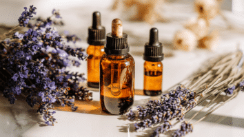 Na imagem ramos de lavanda e frascos de óleo essencial