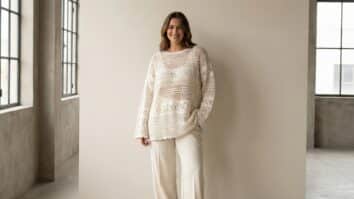 Mulher sorrindo em estilo contemporâneo urbano usando blusa de crochê artesanal em tom off-white, confeccionada em fio de algodão, modelagem moderna levemente oversized