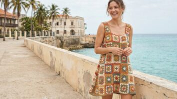 Mulher sorrindo usando vestido de granny squares coloridos ambiente tropical