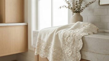 Banheiro ou lavanderia sofisticada com toalha de banho premium finalizada com barrado de crochê de luxo em algodão mercerizado off-white com leve brilho acetinado, barrado largo e ricamente trabalhado com pontos rendados complexos