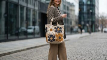Mulher sorrindo com tote bag de crochê tapestry com flores geométricas em ambiente urbano moderno