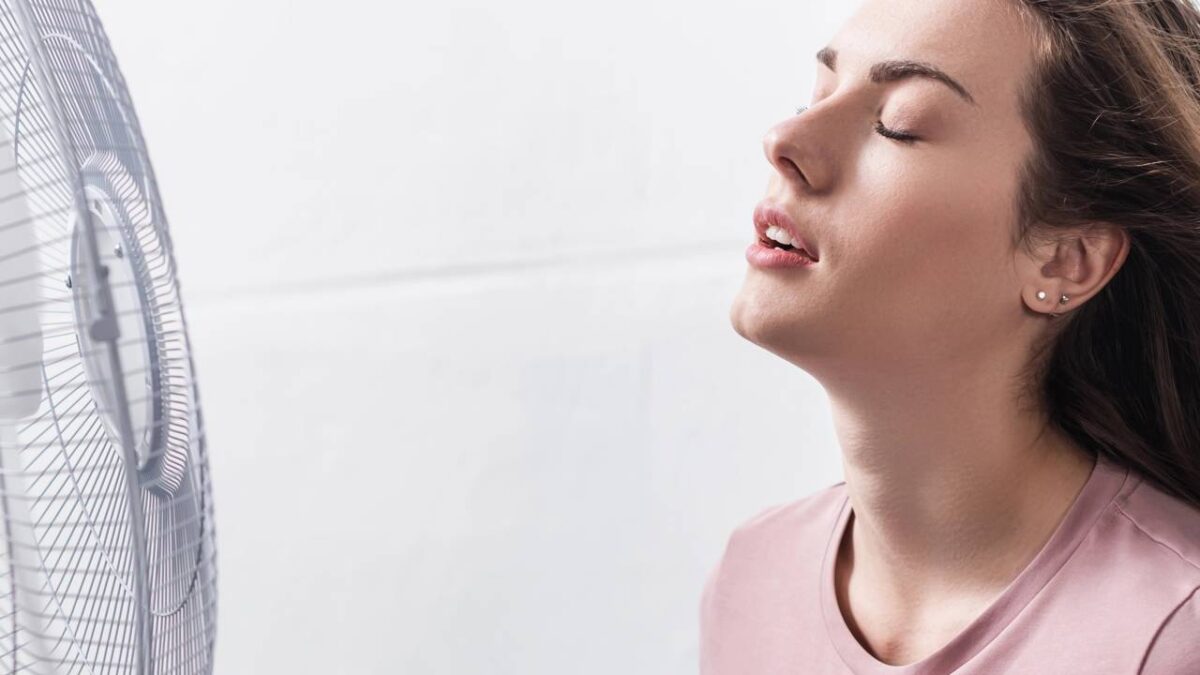 Mulher se refrescando em frente ao ventilador pelo calor extremo
