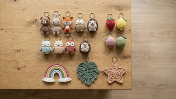 Vista de cima de colecao de chaveiros de croche e amigurumi artesanais organizados sobre bancada de madeira clara