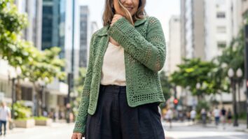 Mulher sorrindo usando blusa de croche artesanal verde natural em algodao de alta qualidade, combinada com roupas neutras modernas em cenario urbano clean com iluminacao natural suave