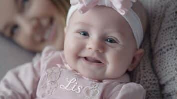 Bebê sorridente deitada com a sua mãe