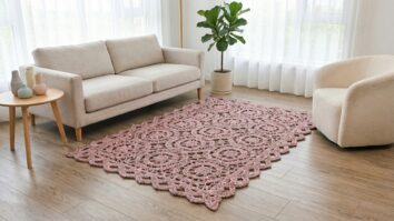 Tapete de croche artesanal cinza e rosa com padrao vazado sobre piso de madeira clara em ambiente elegante
