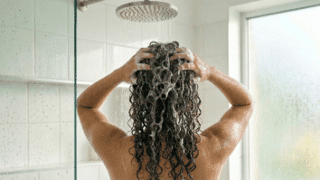 Mulher toma banho lavando o cabelo cacheado
