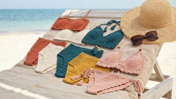 Biquinis de croche artesanal em diferentes cores e estilos organizados sobre espreguicadeira de madeira em ambiente praiano com luz natural