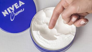 Mulher se preparando para utilizar o creme Nivea da latinha azul
